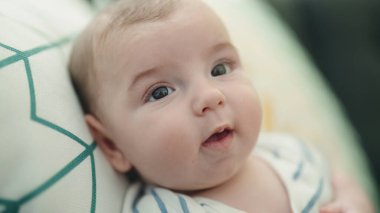 Evdeki rahat ifadesiyle kanepede oturan sevimli beyaz bebek.