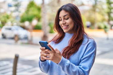 Sokakta akıllı telefon kullanan, kendine güvenen genç İspanyol kadın.