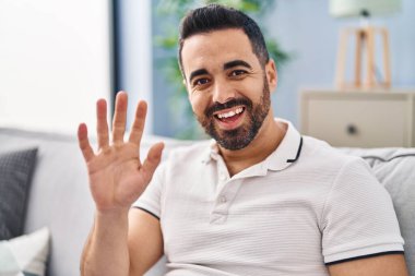 Kanepede oturan İspanyol genç adam evde konuşuyor.