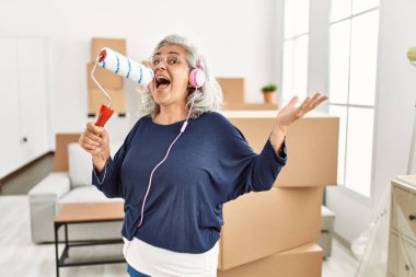 Orta yaşlı, kır saçlı, müzik dinleyip şarkı söyleyen bir kadın..