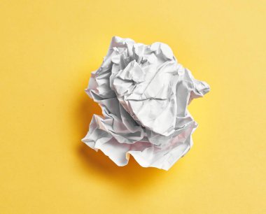  One white crumpled paper ball over isolated yellow background