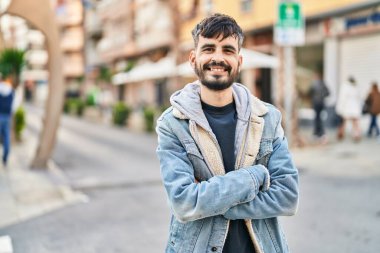 Genç İspanyol adam gülümsüyor. Kendine güveni tam. Sokakta çapraz hareketlerle duruyor.