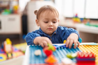 Anaokulundaki masada oturan, inşaat bloklarıyla oynayan sevimli İspanyol kız.