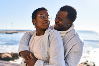 Erkek ve kadın çift sahilde birbirlerine sarılıyorlar.