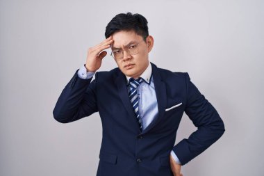 Young asian man wearing business suit and tie worried and stressed about a problem with hand on forehead, nervous and anxious for crisis 