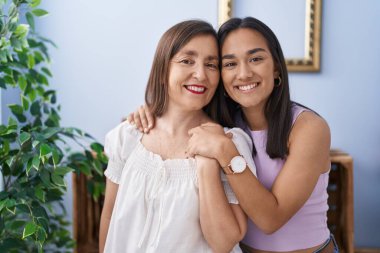 Two women mother and daughter smiling confident hugging each other at home