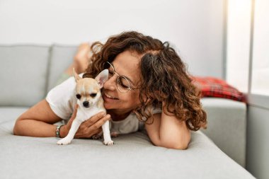 Orta yaşlı İspanyol kadın gülümsüyor, elinde Chihuahua ile.