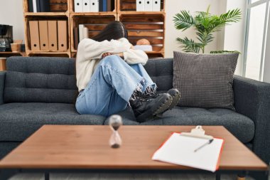 Young hispanic woman patient depressed having psychology session at clinic