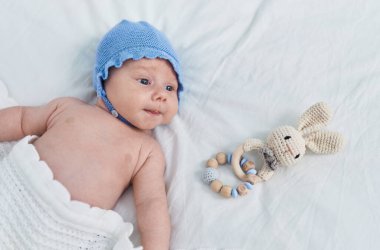 Adorable caucasian baby lying on bed with relaxed expression at bedroom