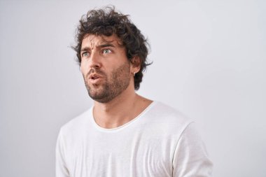 Young hispanic man standing with surprise expression over isolated white background