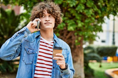 Genç İspanyol adam parkta telefonla konuşuyor.