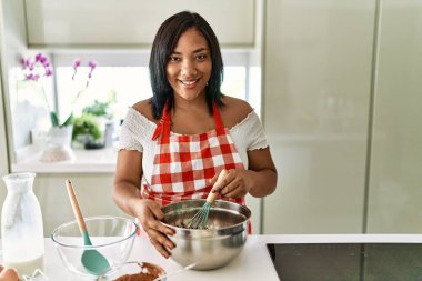 Hispanic brunette woman preparing chocolate cake at the kitchen