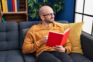 Genç adam evde kanepede oturup kitap okuma