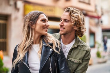 Kadın ve erkek gülümsüyor. Kendilerine güveniyorlar. Sokakta sarılıyorlar.