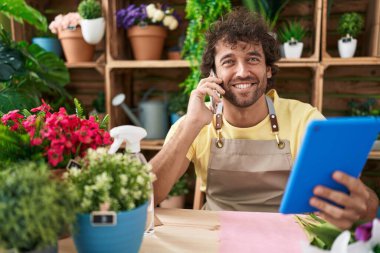 Çiçekçide dokunmatik ped kullanarak konuşan genç İspanyol çiçekçi.