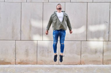 Young hispanic man smiling confident jumping at street