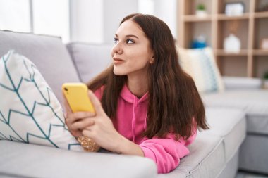 Genç kadın evde koltukta yalan smartphone kullanarak