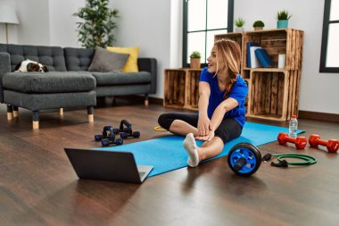 Young caucasian woman smiling confident stretching leg at home