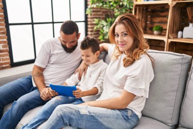Family using touchpad hugging each other sitting on sofa at home