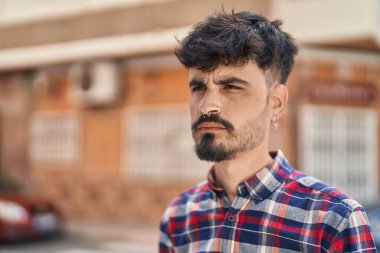 Young hispanic man looking to the side with relaxed expression at street