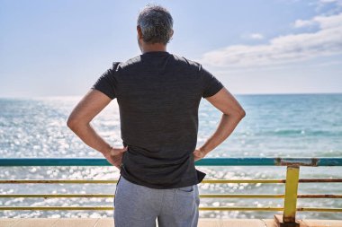 Orta yaşlı İspanyol adam deniz kenarında spor giyer.