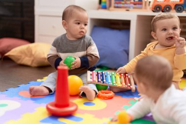 Anaokulunda yerde oturmuş oyuncaklarla oynayan bir grup çocuk.