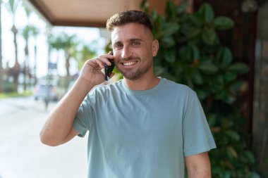 Genç İspanyol adam gülümsüyor. Kendine güveniyor. Sokakta akıllı telefondan konuşuyor.