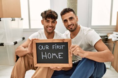 İki İspanyol erkek gülümsüyor. İlk ev tahtamızı yeni evimizde tutuyorlar.