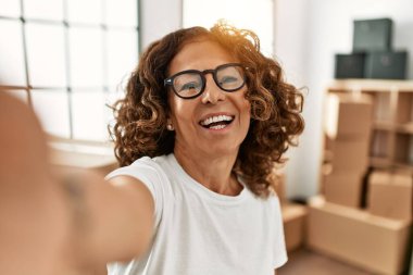 Orta yaşlı, kendine güvenen İspanyol bir kadın yeni evindeki kameranın önünde selfie çekiyor.