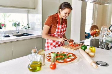 Mutfakta domates keserken gülümseyen güzel İspanyol kadın.