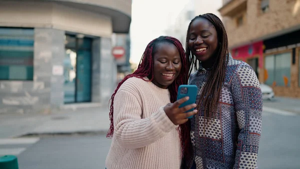 Two african american friends smiling confident using smartphone at street