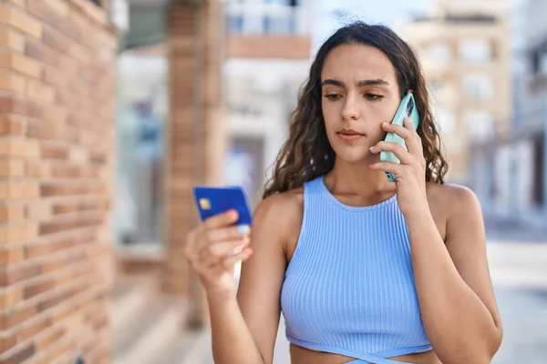 若いです美しいですヒスパニック女性話して上のスマートフォン保持クレジットカードでストリート — ストック写真