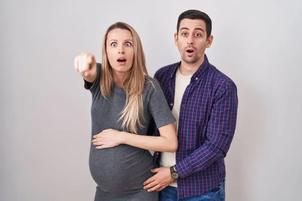 Casal Jovem Esperando Bebê Sobre Fundo Branco Apontando Com Dedo — Fotografia de Stock