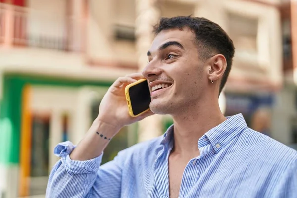 若いヒスパニック系の男が路上でスマートフォンで自信を持って話して笑っている — ストック写真