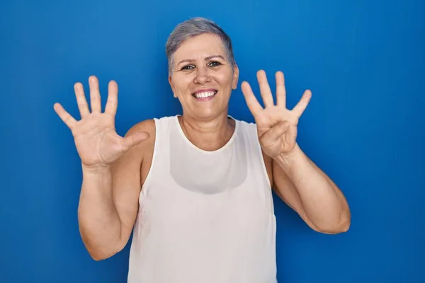 中年Cucasian女性立っています上の青の背景ショーと指番号9と指摘しながら笑顔自信と幸せ — ストック写真