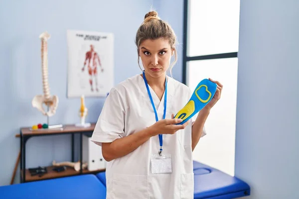 Young Woman Holding Shoe Insole Physiotherapy Clinic Skeptic Nervous Frowning — Stok fotoğraf