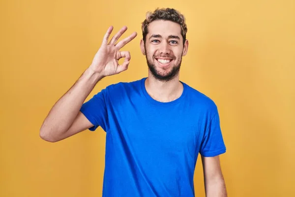 黄色い背景の上に髭を生やしたヒスパニック系の男性は 手と指でOkサインをして積極的に笑っています 成功した表現 — ストック写真