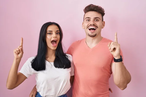 Young Hispanic Couple Standing Pink Background Pointing Finger Successful Idea — Fotografia de Stock