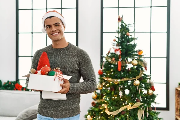 Young Hispanic Man Smiling Confident Holding Box Christmas Decoration Home — стоковое фото