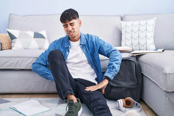 Young Hispanic Man Sitting Floor Studying University Suffering Backache Touching — Zdjęcie stockowe
