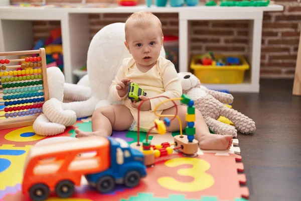 可爱的高加索婴儿抱着圈圈玩具坐在幼儿园的地板上 — 图库照片
