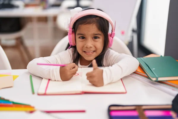Adorable Hispanic Girl Student Sitting Table Drawing Notebook Listening Music — Fotografia de Stock