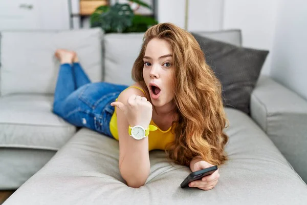 Jeune Femme Caucasienne Couchée Sur Canapé Aide Smartphone Surpris Pointant — Photo