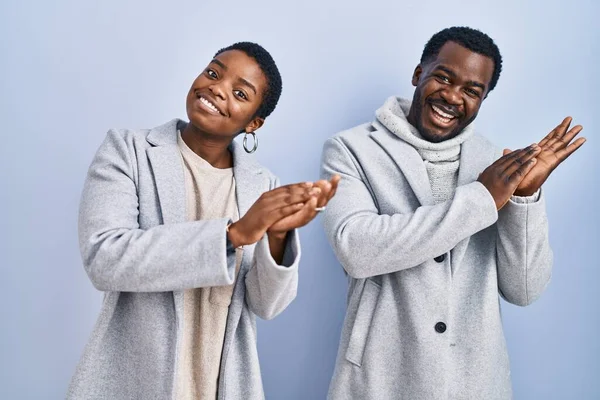 一对年轻的非洲裔美国夫妇站在蓝色的背景上 一起拍手鼓掌 欢快地 快乐地 自豪地手挽手 — 图库照片