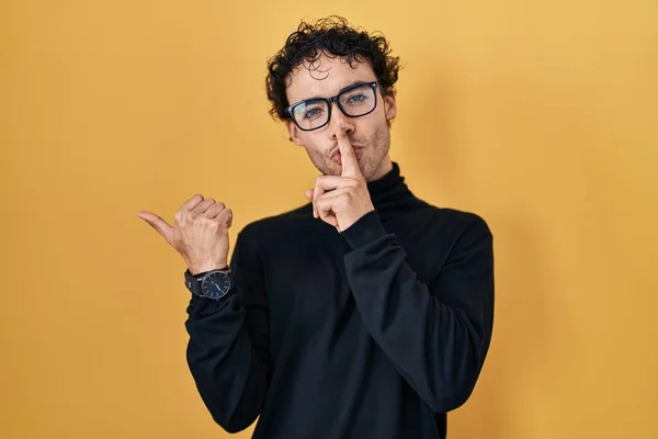 Hispanic Man Standing Yellow Background Asking Quiet Finger Lips Pointing — Stock Photo, Image
