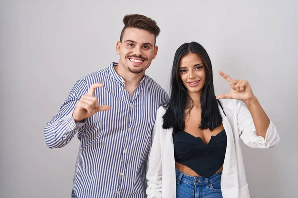 Young Hispanic Couple Standing White Background Smiling Confident Gesturing Hand — Stock Fotó