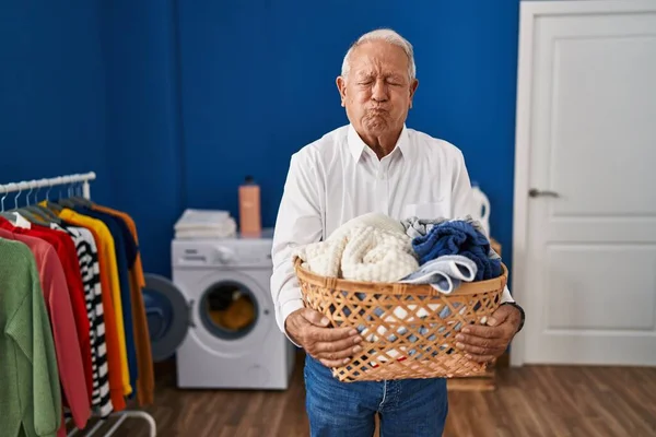 一个白发苍苍的老人在家里拿着洗衣篮 满脸都是笑脸 气喘吁吁的 嘴被空气吹胀 — 图库照片