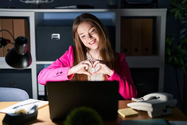 夜のオフィスで働く若い白人女性が手でハートのシンボルの形をするのが大好きです ロマンチックなコンセプト — ストック写真