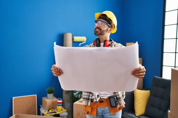 Young Hispanic Man Worker Smiling Confident Looking Blueprints New Home — стоковое фото