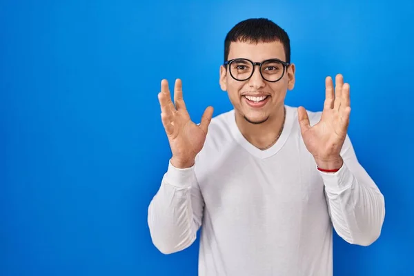 年轻的阿拉伯男子身穿休闲装 戴着眼镜 高举双臂 睁大眼睛 兴奋地尖叫着 庆祝着成功 获奖者概念 — 图库照片